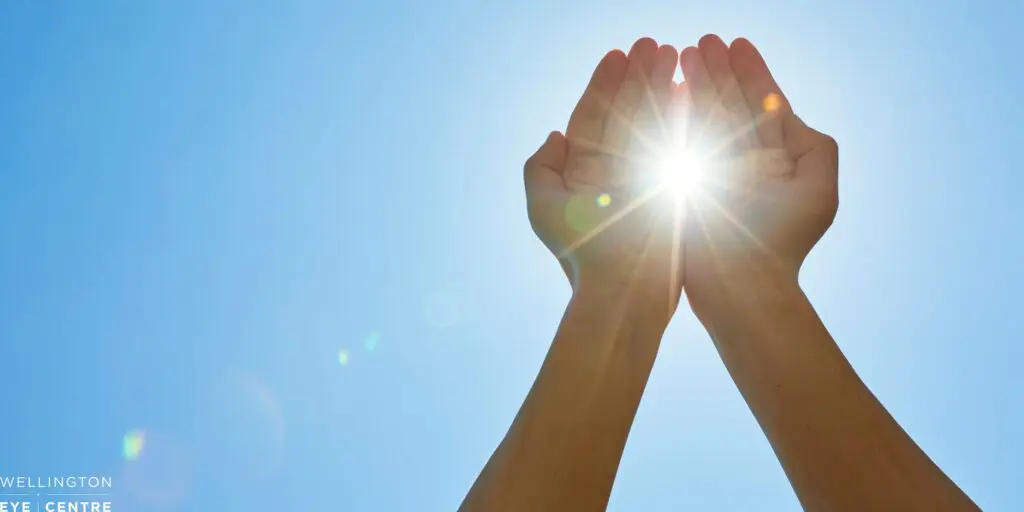 Sun light shining through hands with blue sky behind