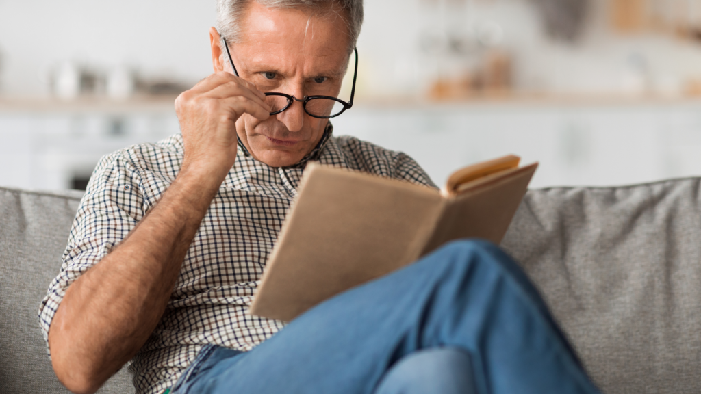 Older man using reading glasses, illustrating age-related vision changes after LASIK.