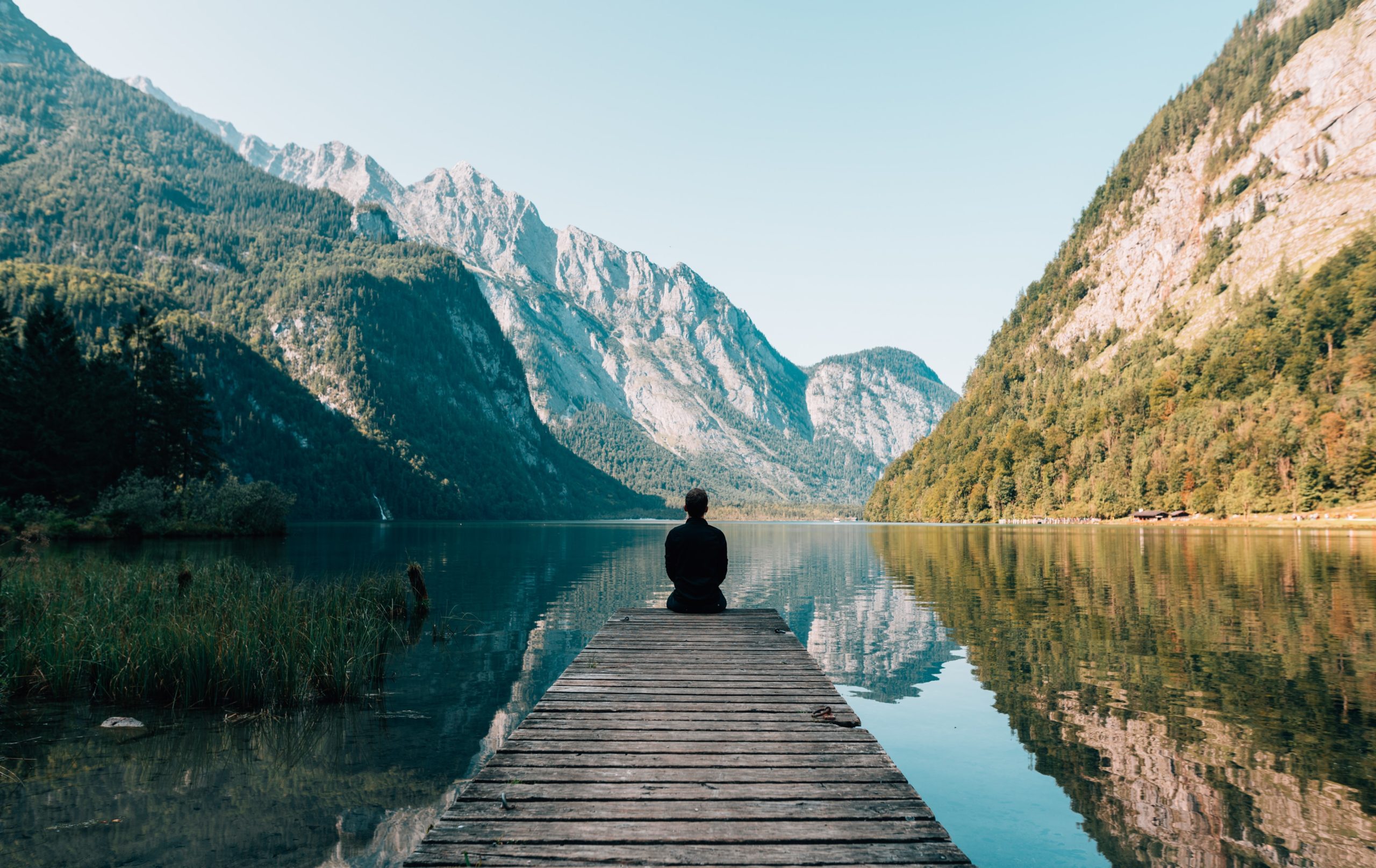 Man sitting on wharf looking at mountains
